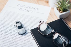 Policy papers in an insurance company office with a pair of glasses and model car.