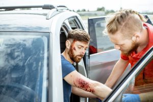 A man sat in a car with visible injuries being checked out