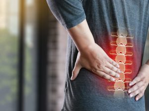 A person holds their lower back with the initial symptoms of cauda equina syndrome.