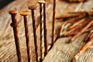A row of old and rusty nails on a wooden surface.