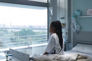 A woman sits on her hospital bed after being harmed by a pharmacy error.