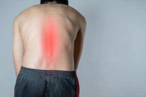 A man stretching with lower back pain highlighted in red