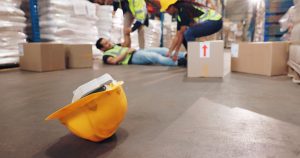 An injured man is lying on the floor while two colleagues help him.