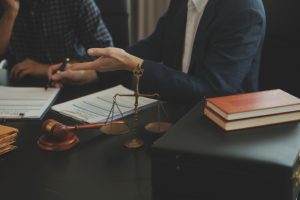 A solicitor and their client discussing a Lime Bike accident claim in an office surrounded by documents, a set of justice scales and judge's gavel