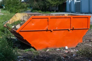 An orange skip outside loaded with detritus