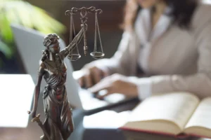 A solicitor sat at a desk with a statue of Lady Justice and a book working on a paralysis compensation claim