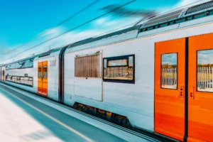 A white train with orange doors at a train station