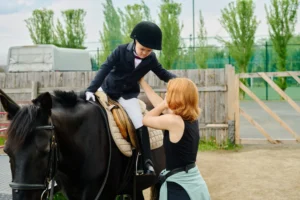A child is being helped off a horse during a lesson. 