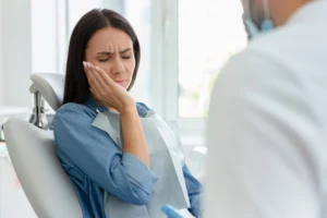 A woman holding her jaw in pain considering making a dental negligence compensation claim.