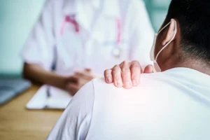 A man holding his shoulder while consulting a doctor