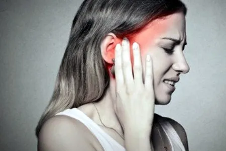 a woman with tinnitus holding her ear with the pain